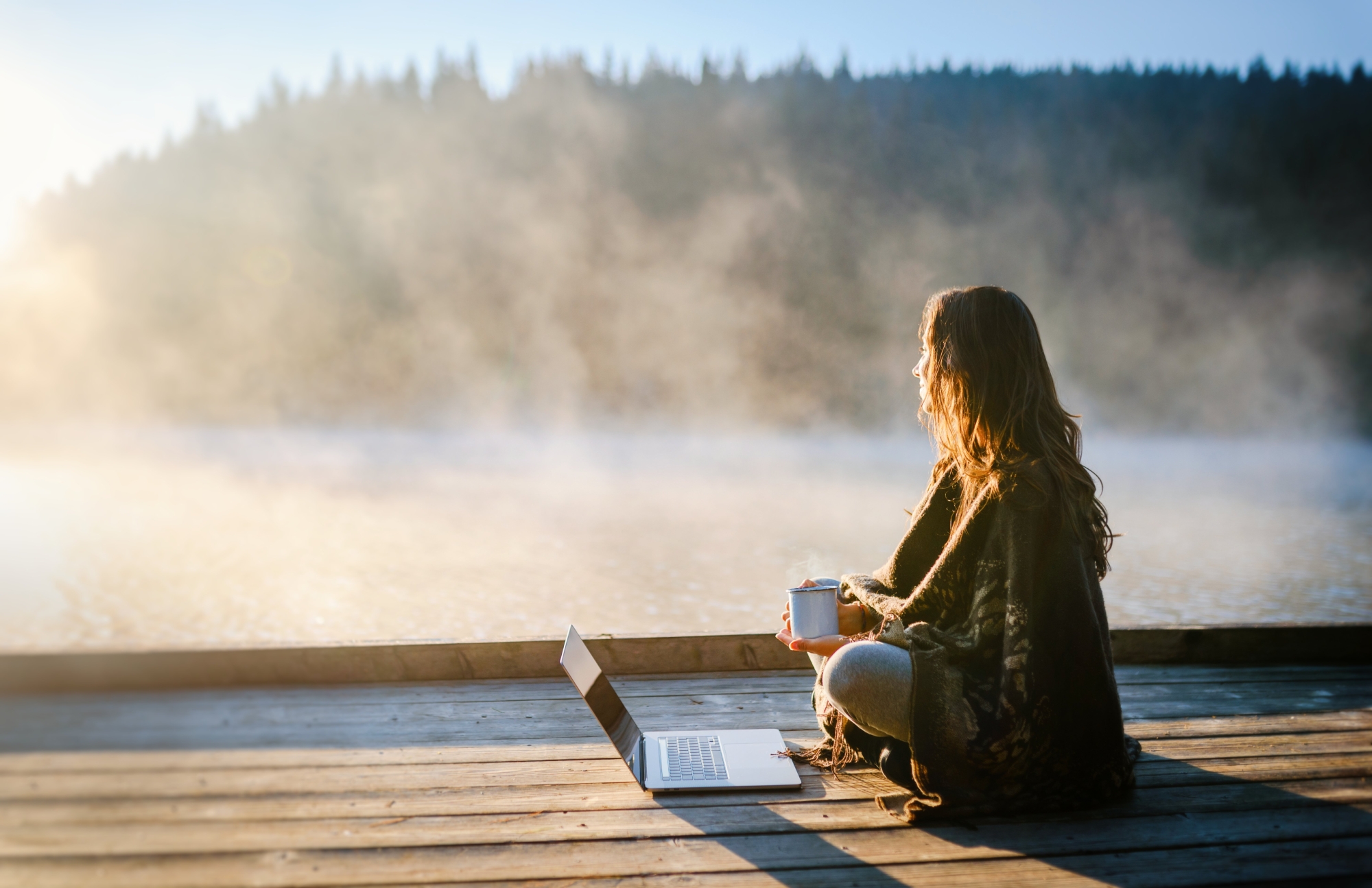 Femme assise devant un ordinateur au bord de l'eau