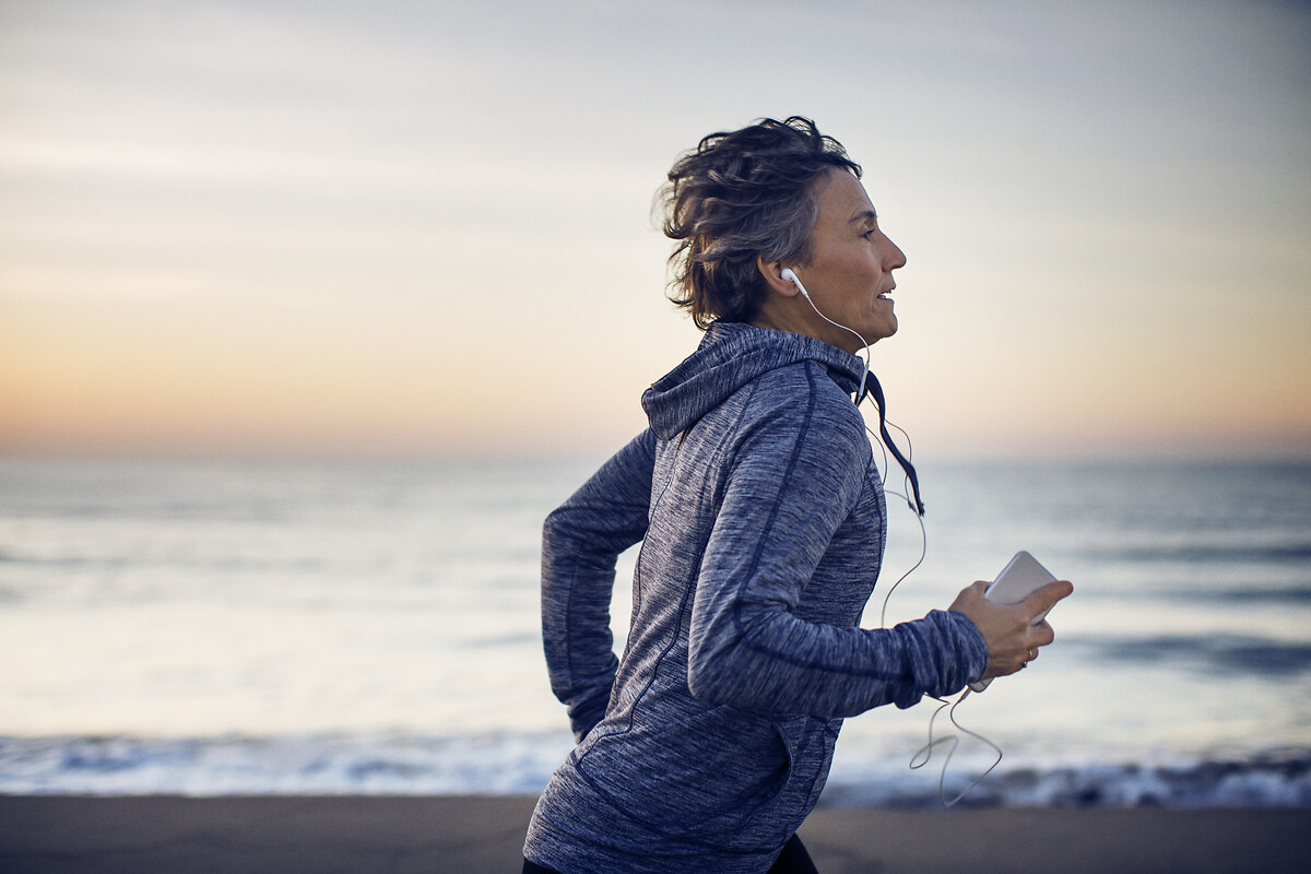  Une femme fait son jogging sur la plage en écoutant de la musique