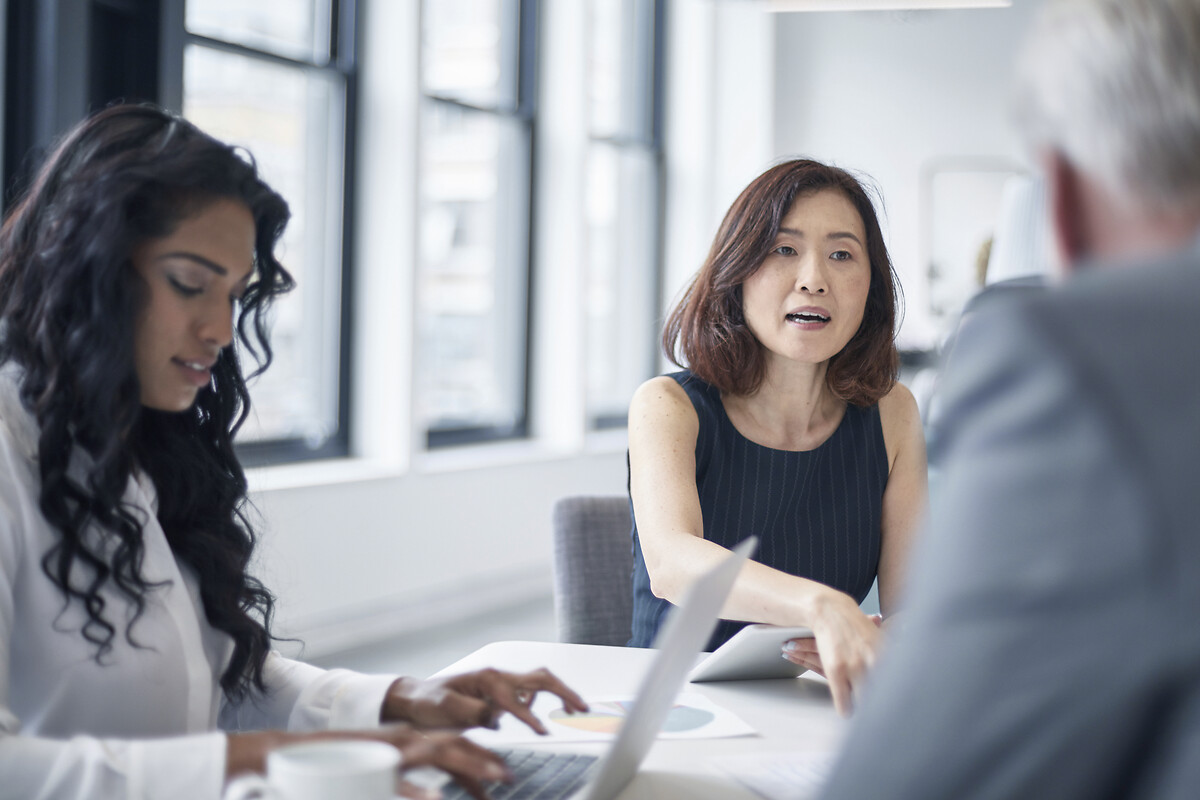 Un homme et une femme discutent lors d'une réunion dans un bureau. La femme à gauche utilise un ordinateur portable.