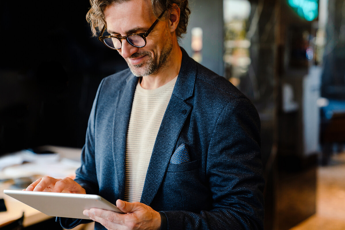 Cette photographie représente un homme qui travaille sur une tablette.