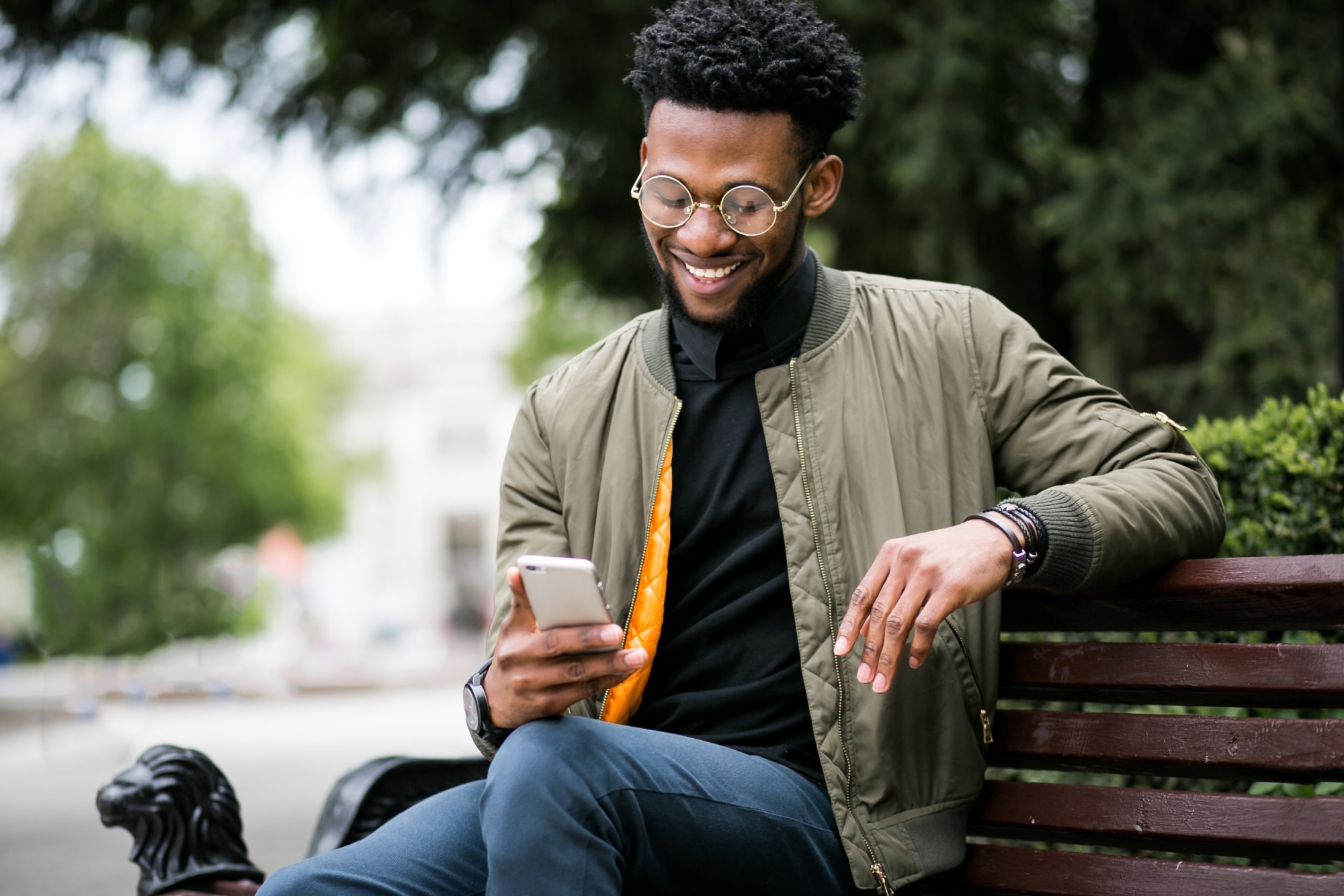 Homme assis sur un banc en train de regarder son téléphone
