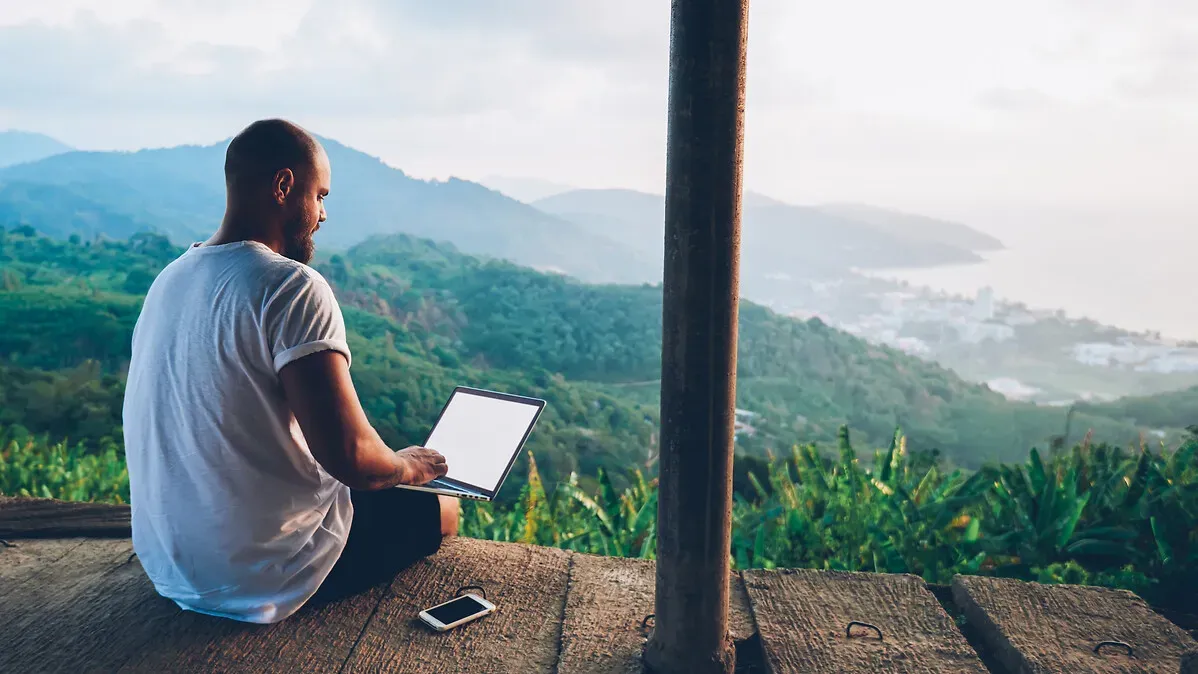 Homme sur un ordinateur portable tout en appréciant la vue sur le paysage