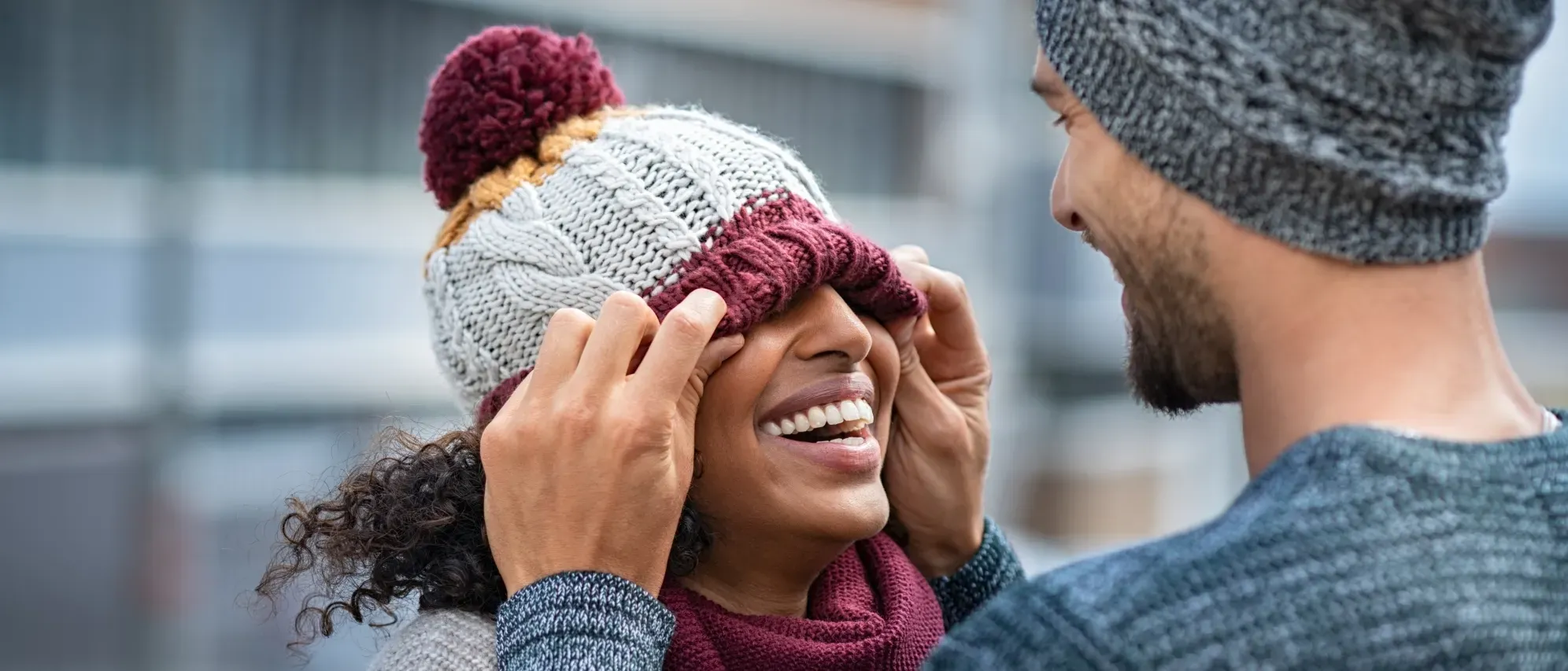  Un couple souriant dans la rue, portant des bonnets à pompon.