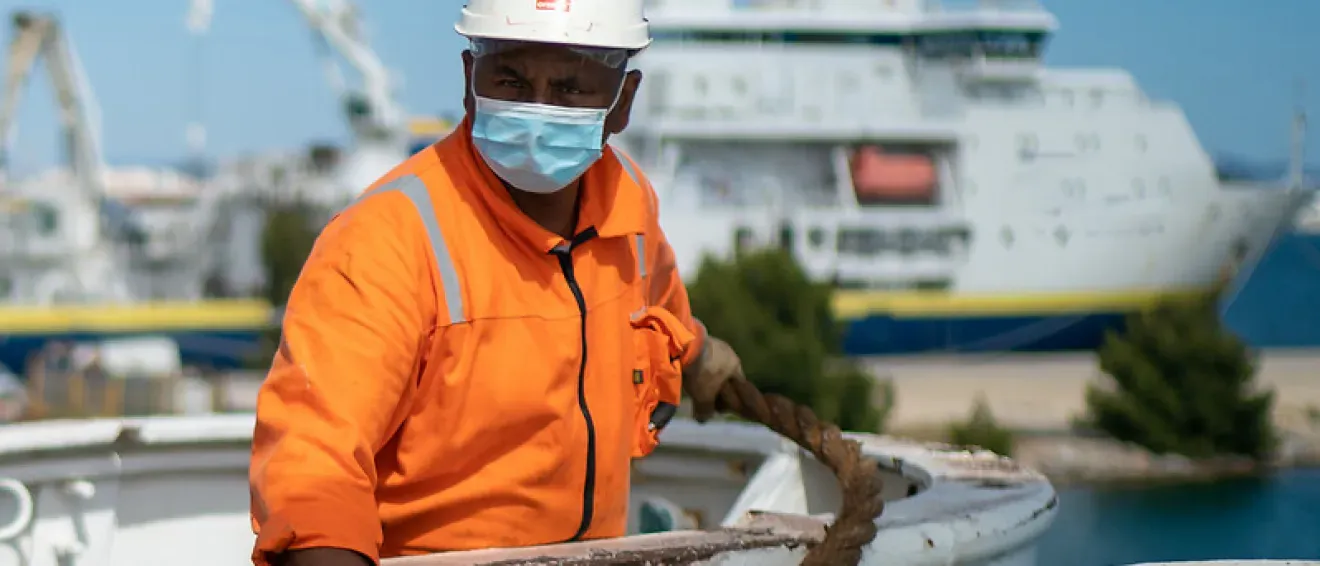 A man working on the deck of a ship wearing a face mask