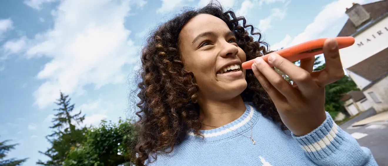 Une jeune fille parle au téléphone avec le sourire.