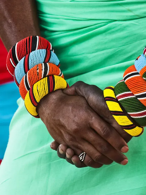 Gros plan sur les bras d'une femme portant des bracelets colorés en perles, bijoux traditionnels africains.