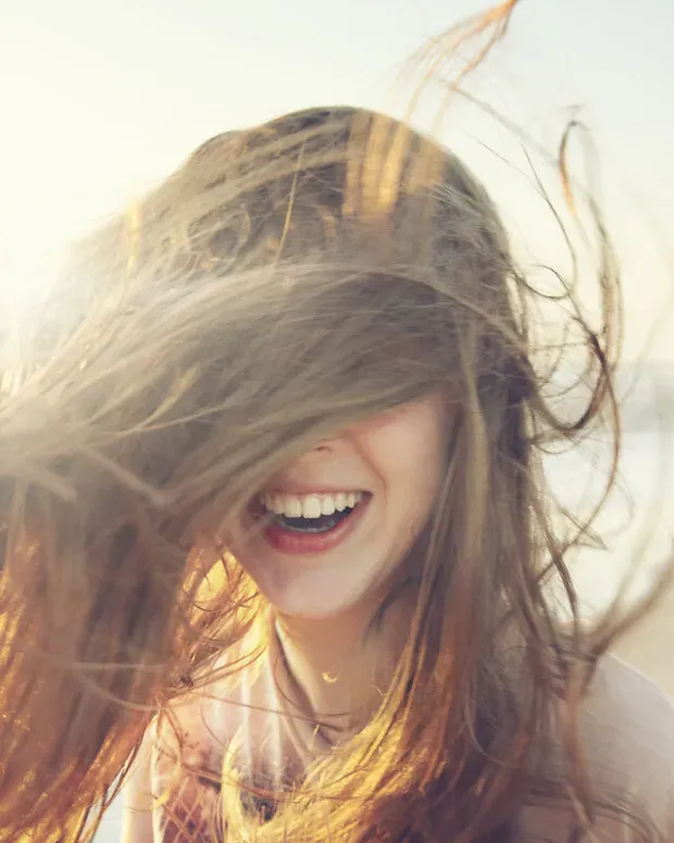 Femme en extérieur, avec le sourire, cheveux aux vents