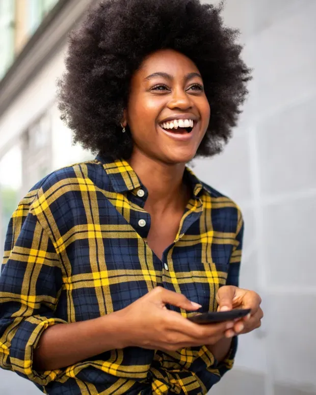 Femme souriante marchant avec un téléphone dans les mains