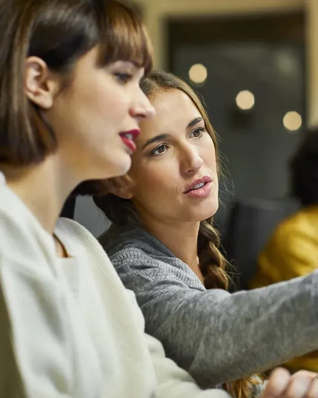  Une femme montre son écran d'ordinateur à sa collègue