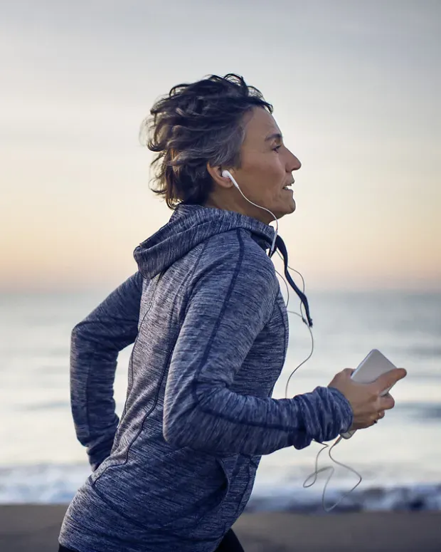  Une femme fait son jogging sur la plage en écoutant de la musique