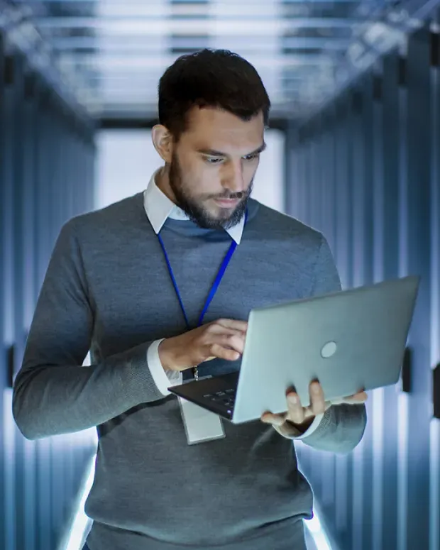 Un homme travaille sur son laptop dans un data center