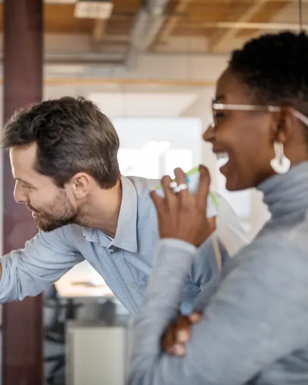 Une femme rit de ce que sa collègue a écrit sur des Post-it.