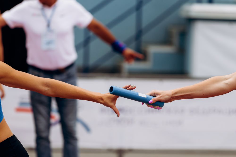 2 mains de femmes, bâton de relai, logo composite Paris 2024 - Orange
