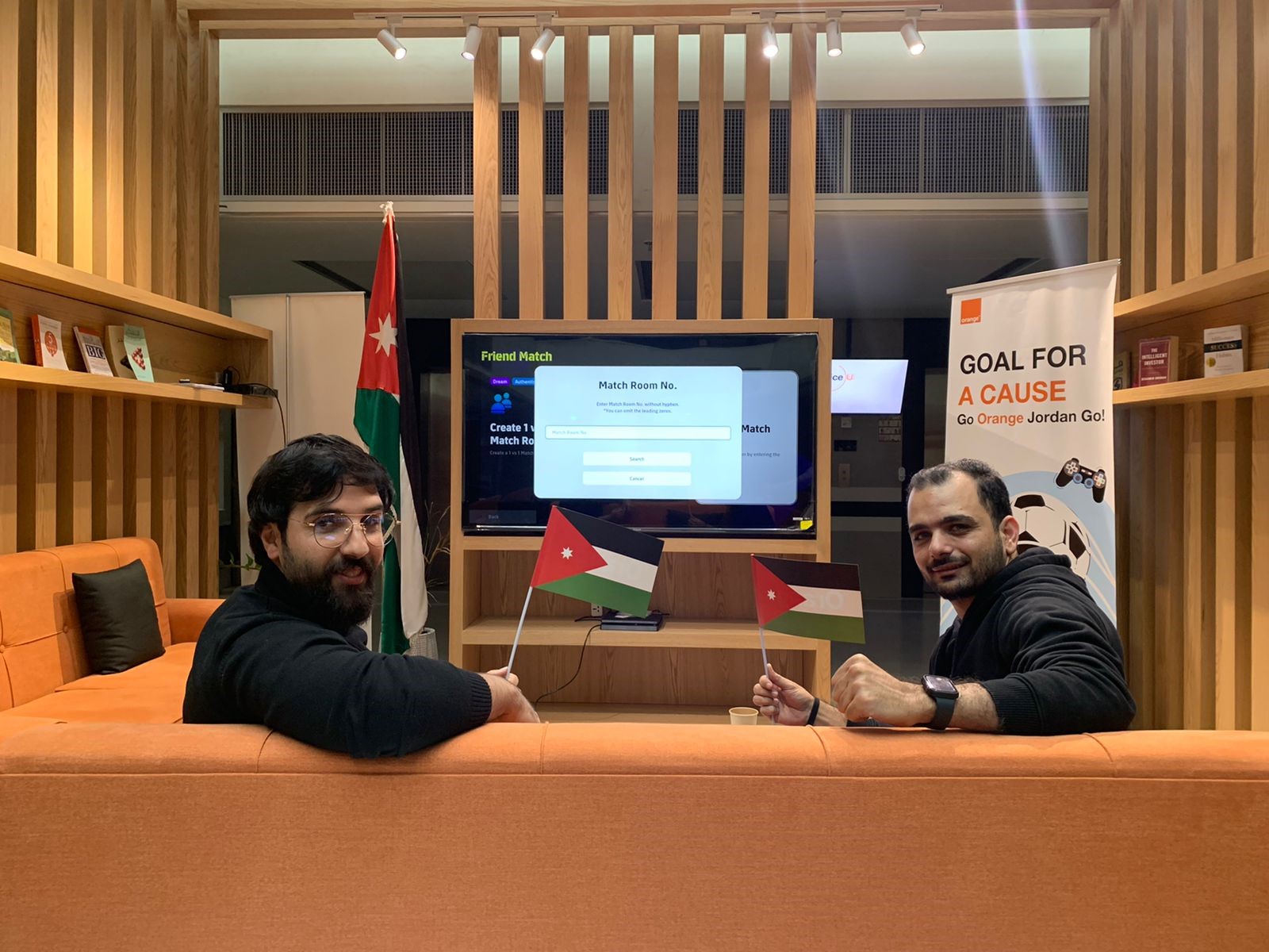 Photo de deux hommes assis sur un canapé devant une télé