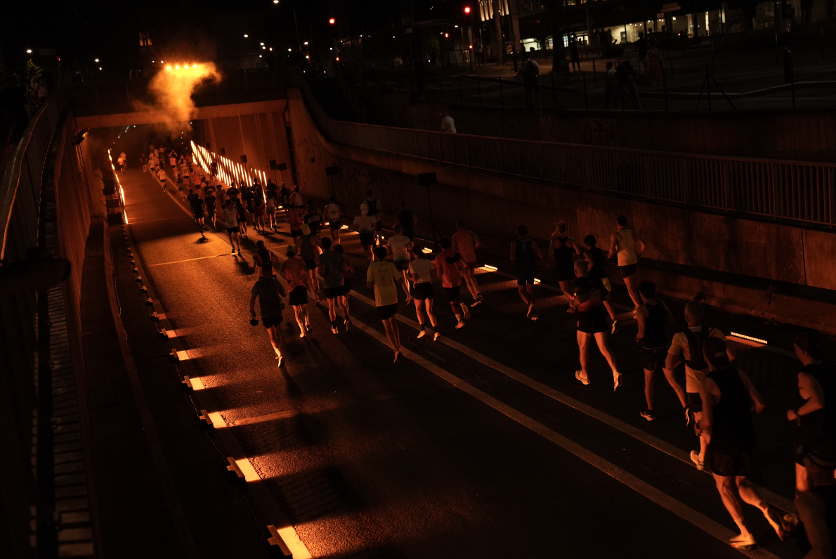 Marathon runners enter a night tunnel lit up in Orange colors