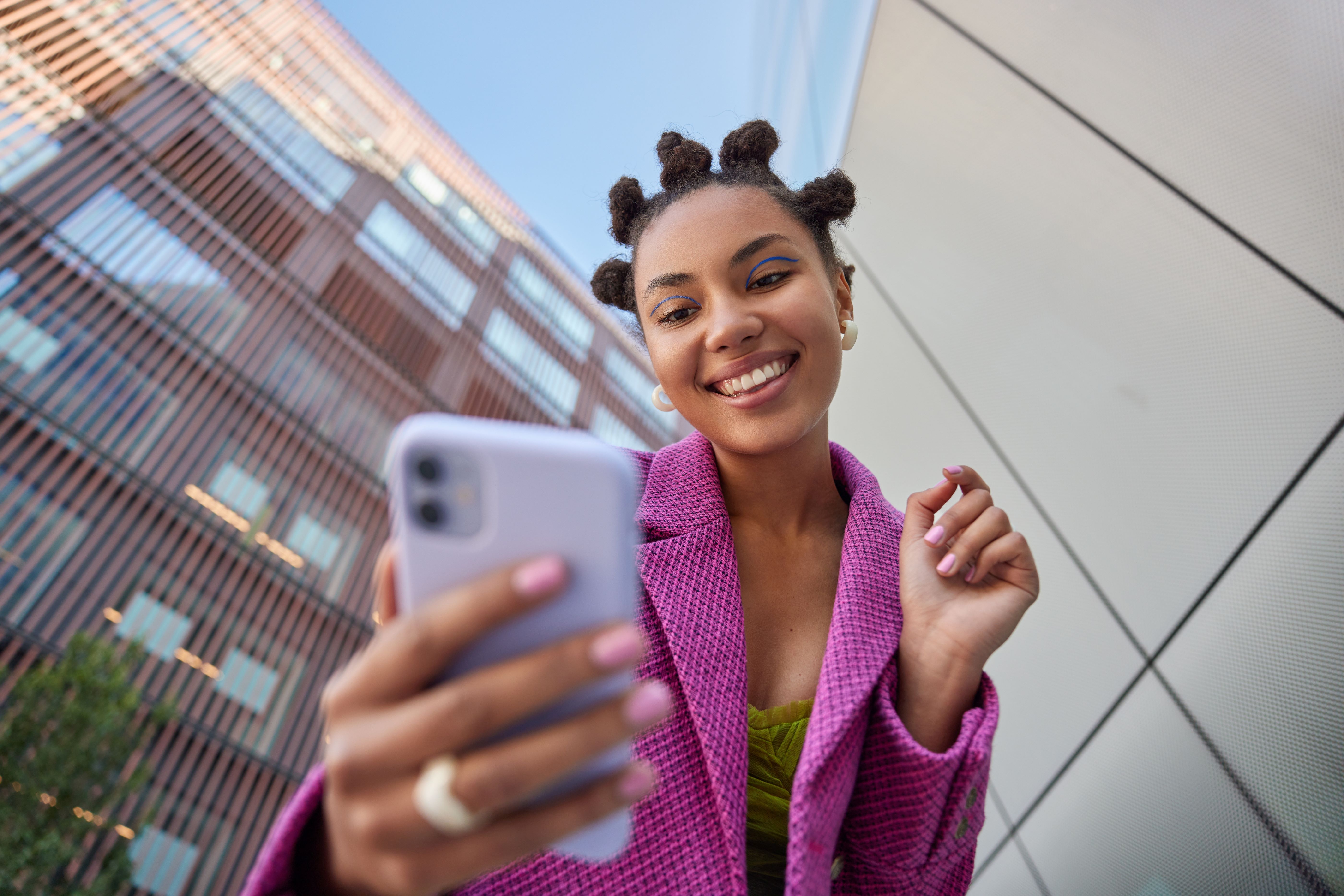 Jeune femme souriant devant son téléphone, photo contre plongée