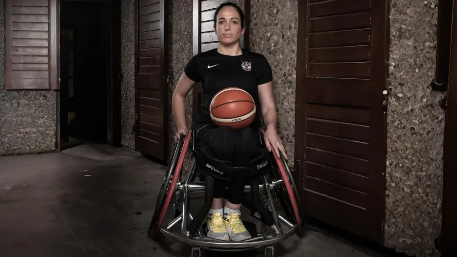 Anne-Sophie avec un ballon de basket sur les genoux, dans un fauteuil roulant de sport