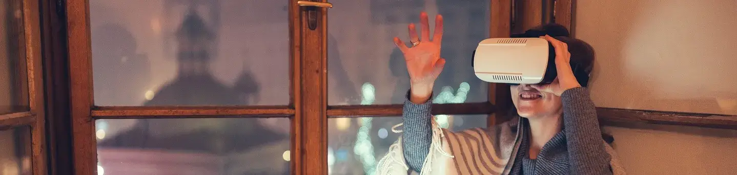 jeune femme la nuit sur son canapé, souriante avec casque réalité virtuelle