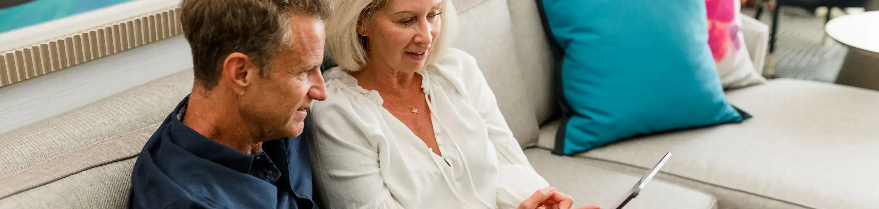 Un homme et une femme âgées sur un canapé regarde une tablette