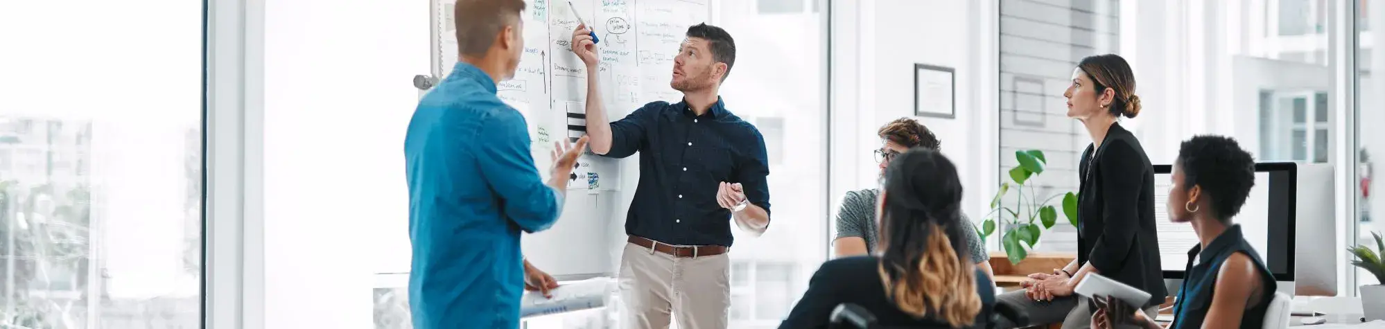 Photo d'un homme présentant des informations sur un tableau à 2 hommes et 3 femmes