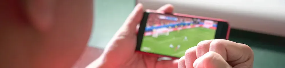 Un supporter tient son smartphone entre les mains et suit un match