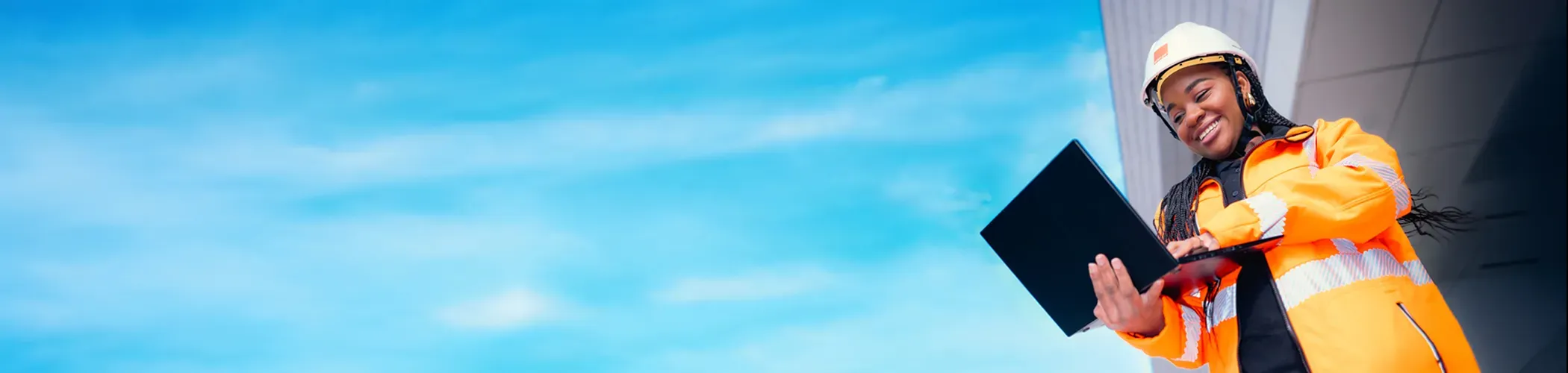 An Orange technician smiling and working on her laptop