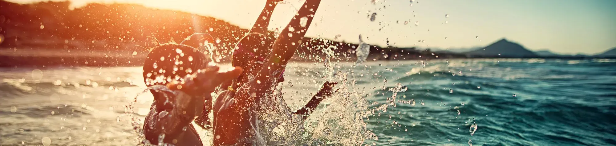 Des enfants se baignent dans la mer avec un couché de soleil