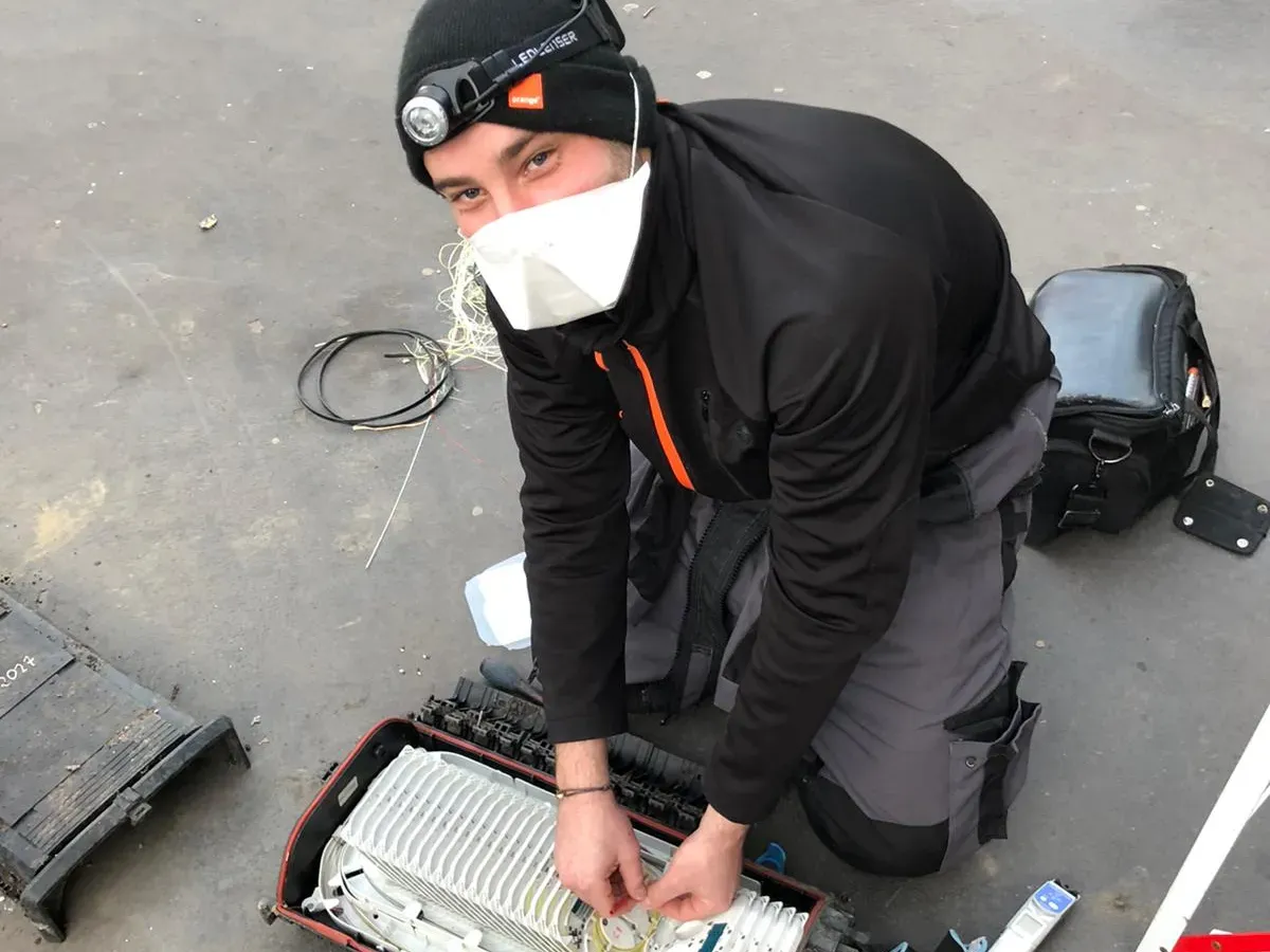 Un technicien Orange au travail avec un masque
