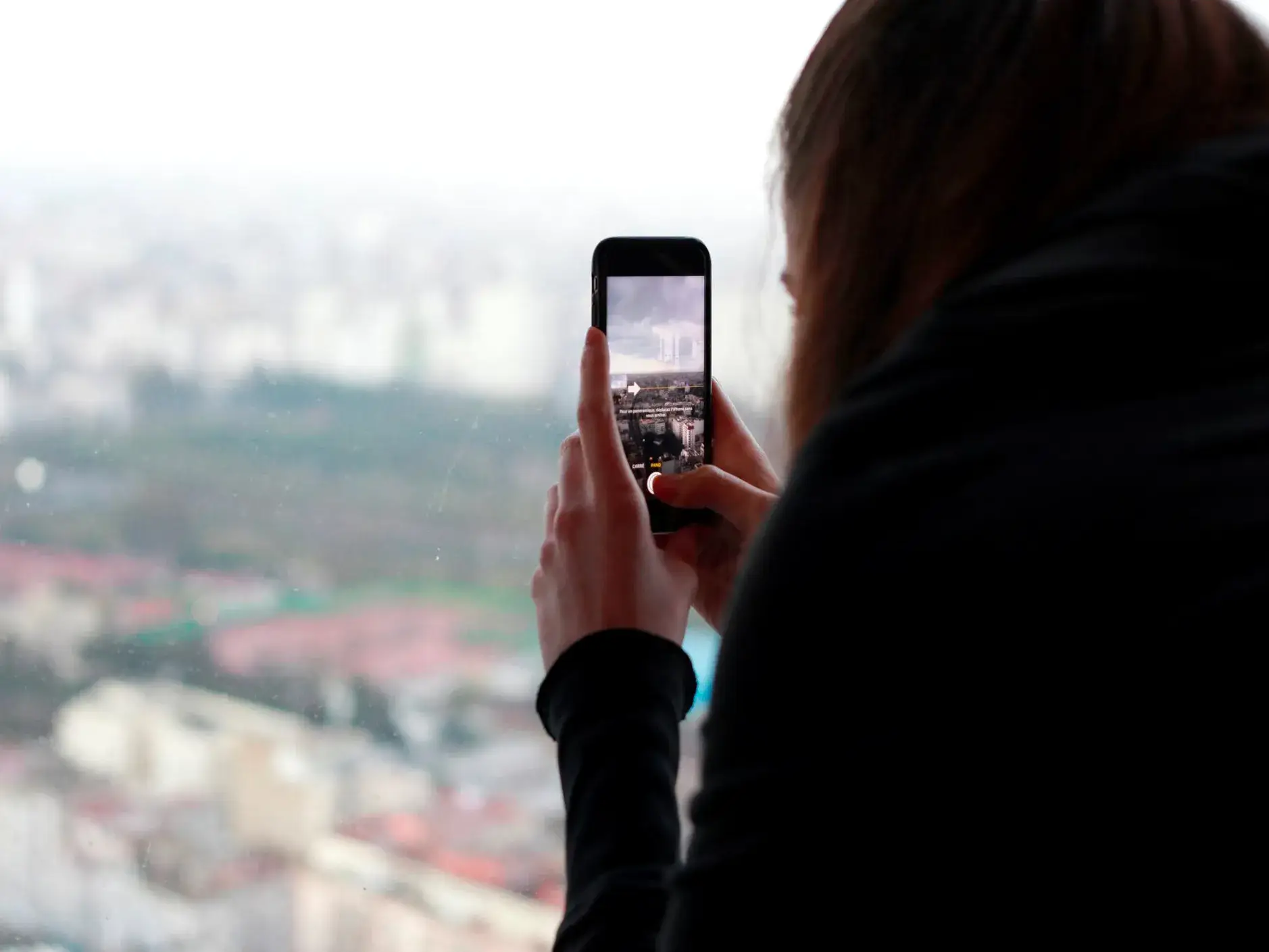 Jeune fille photographie avec son mobile a travers une vitre