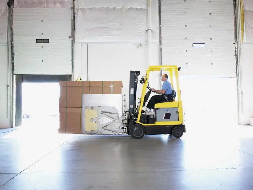 Un homme conduisant un chariot élévateur dans un entrepôt