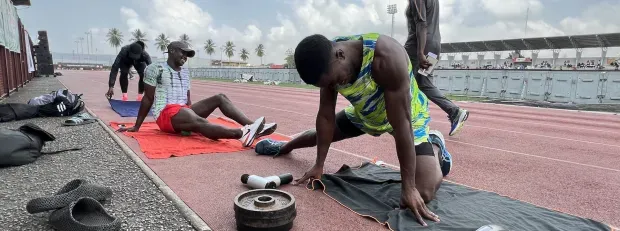 Photo d'Arthur Cissé qui s'échauffesur un terrain de course avec d'autres athlètes