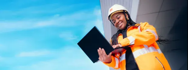 An Orange technician smiling and working on her laptop